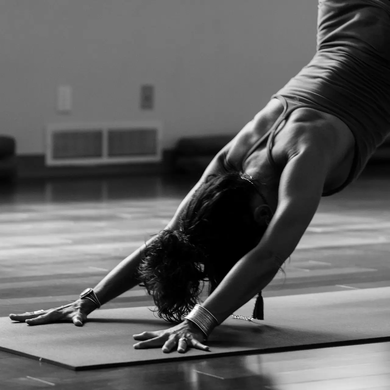 woman in black tank top and black pants bending her body on floor